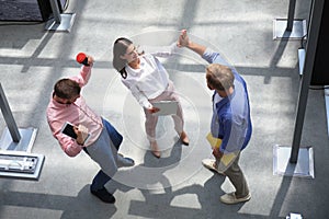 Top view of young modern colleagues in smart casual wear working together while spending time in the office.