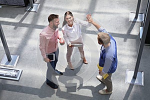 Top view of young modern colleagues in smart casual wear working together while spending time in the office.