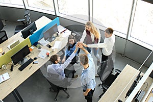 Top view of young modern colleagues in smart casual wear working together while spending time in the office.