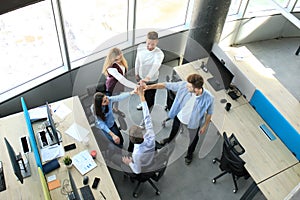 Top view of young modern colleagues in smart casual wear working together while spending time in the office.