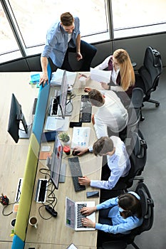 Top view of young modern colleagues in smart casual wear working together while spending time in the office.