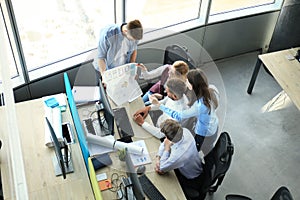 Top view of young modern colleagues in smart casual wear working together while spending time in the office.