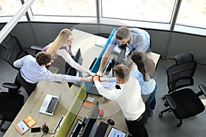 Top view of young modern colleagues in smart casual wear working together while spending time in the office.