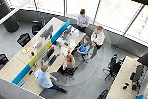 Top view of young modern colleagues in smart casual wear working together while spending time in the office.