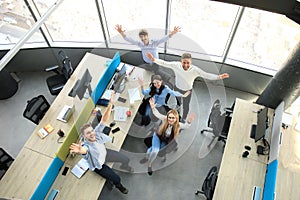 Top view of young modern colleagues in smart casual wear working together while spending time in the office.