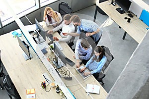 Top view of young modern colleagues in smart casual wear working together while spending time in the office.