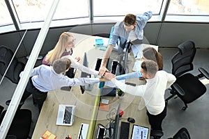 Top view of young modern colleagues in smart casual wear working together while spending time in the office.