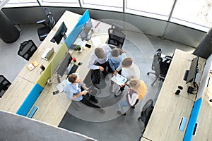 Top view of young modern colleagues in smart casual wear working together while spending time in the office.