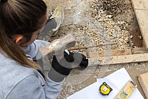 Top view of young woman hammering a nail on a construction site