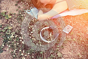 top view of young woman lying nearing headphone in the flower field