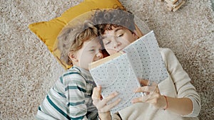 Top view of young woman reading book to little child indoors at home