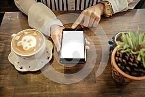 top view. young woman sitting in restaurant and using mobile phone has coffee cup with latte art and place on wooden table