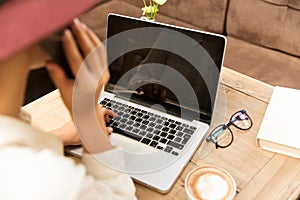 Top view of young woman using laptop while talking on mobile phone,