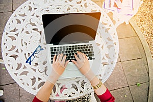 Top view of young working woman using laptop and reading annual report document at work. Business woman working at her desk