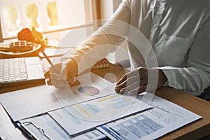 Top view of young working woman using laptop and reading report , graphs , charts, document at work. Business woman working at her