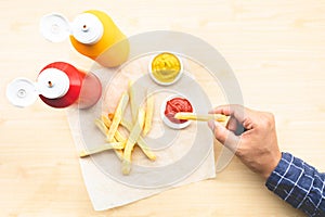 Top view of youngman enjoy eating with french fried and dipping sauce  mustard,ketchup  on wood table background