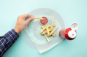 Top view of youngman enjoy eating with french fried and dipping  tomato sauce  ketchup  on color table background photo