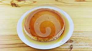 Top view zoom out from whole round homemade soft flan served with caramel syrup