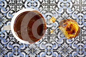 Top viwe of cup with hot chocolate and custard tart called pastel de nata on portuguese tiles background photo