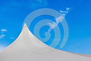 Top of white canvas tent against blue sky background.