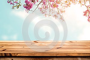 Top of wood table with pink cherry blossom flower on sky background