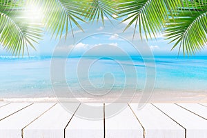 Top of wood table with seascape and palm leaves, blur bokeh light of calm sea and sky at tropical beach background.blurred blue