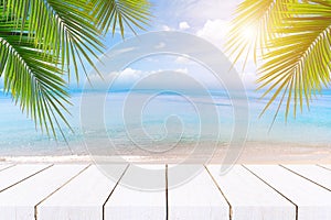 Top of wood table with seascape and palm leaves, blur bokeh light of calm sea and sky at tropical beach background.blurred blue