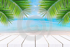 Top of wood table with seascape and palm leaves, blur bokeh light of calm sea and sky at tropical beach background.blurred blue