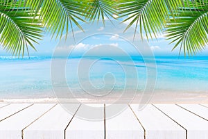 Top of wood table with seascape and palm leaves, blur bokeh light of calm sea and sky at tropical beach background.blurred blue