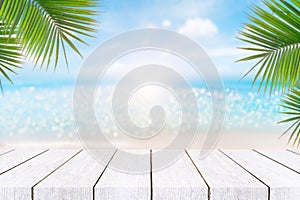 Top of wood table with seascape and palm leaves, blur bokeh light of calm sea and sky at tropical beach background.blurred blue