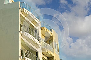 Top of the yelow building with glass balconies in St paul bay Malta, with blue sky with clouds