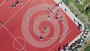 A topdown aerial view of teenagers playing basketball on the basketball court.