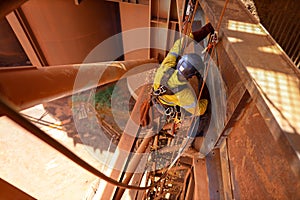 Tope view abseiler rope access repairer hanging in fall restraint position performing oxy acetylene cutting metal beam photo
