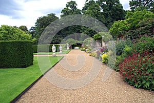 Topiary garden path with ornaments, bench, and herbaceous border