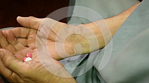 The topic of Alzheimer`s disease in the elderly. an old man holding pills in his hands, scattered memory, dementia in the elderly.