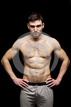 Topless man stood isolated on a black background