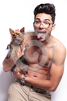 Topless young man holding puppy and panting