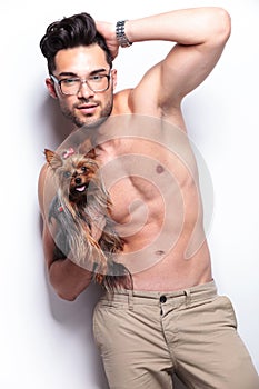 Topless young man holds puppy while posing