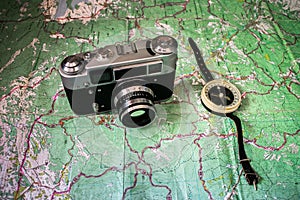 Topographical map with tourist routes is under the old camera and compass. The Concept of Travels