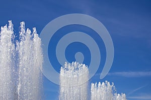 Tops of large fountain jets gushing upwards against blue sky