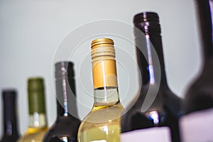 Tops of red and white wine bottles on light background