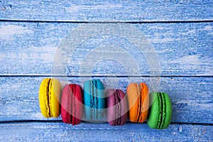 Topshot of sweet and colourful french macaroons on blue wooden background