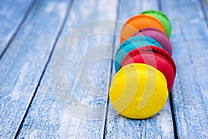 Topshot of sweet and colourful french macaroons on blue wooden background