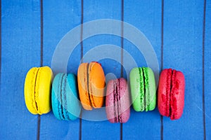 Topshot of sweet and colourful french macaroons on blue wooden background