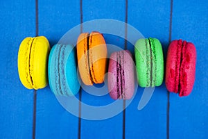 Topshot of sweet and colourful french macaroons on blue wooden background