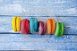 Topshot of sweet and colourful french macaroons on blue wooden background