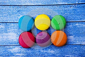 Topshot of sweet and colourful french macaroons on blue wooden background