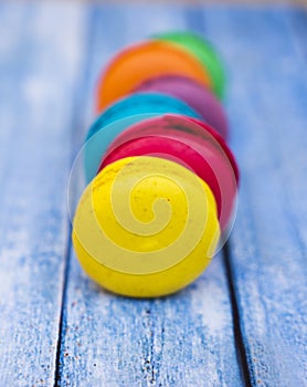 Topshot of sweet and colourful french macaroons on blue wooden background