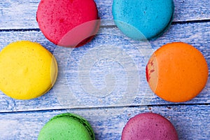 Topshot of sweet and colourful french macaroons on blue wooden background