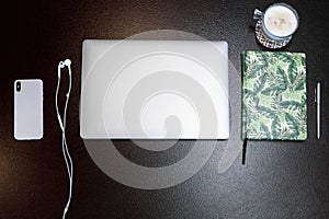 Topview laptop with smartphone and headphones with green sketchbook and pen